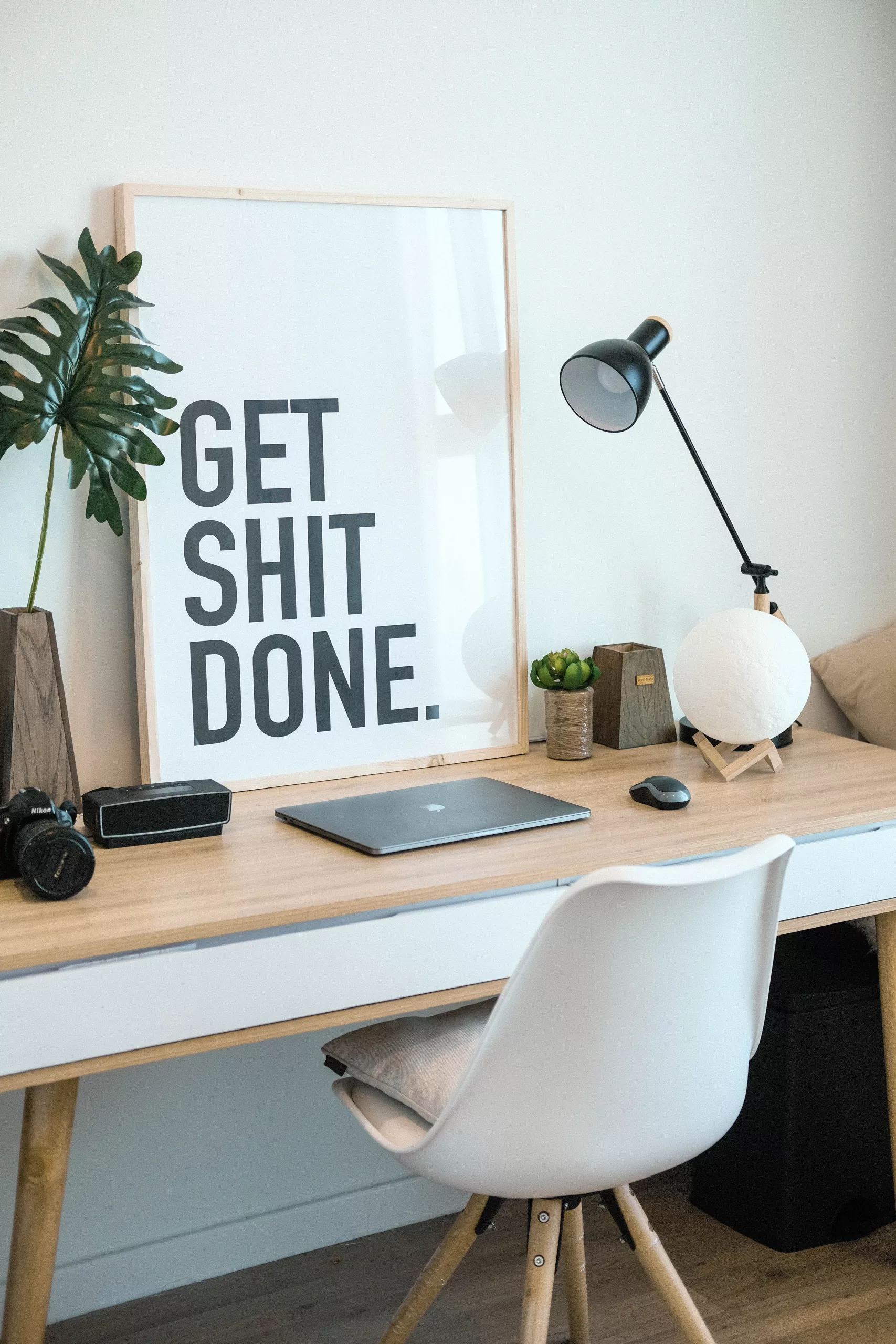 Arbeidsplass med plakat hvor det står "Get shit done"